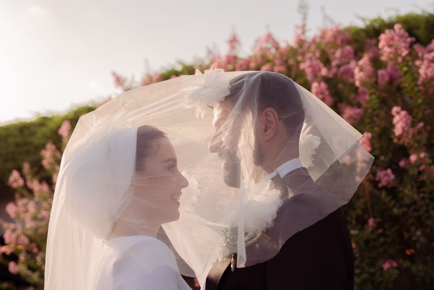 A romantic wedding photo sequence showing a flowing veil catching the breeze against a backdrop of pink flowering trees.