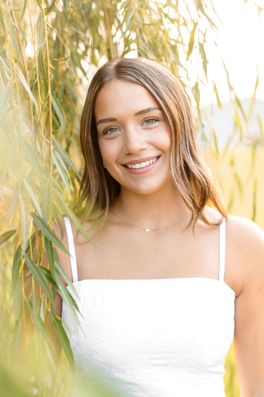 A series of outdoor portraits showing someone in a white top against a soft, dreamy background of willow branches in North Iowa.
