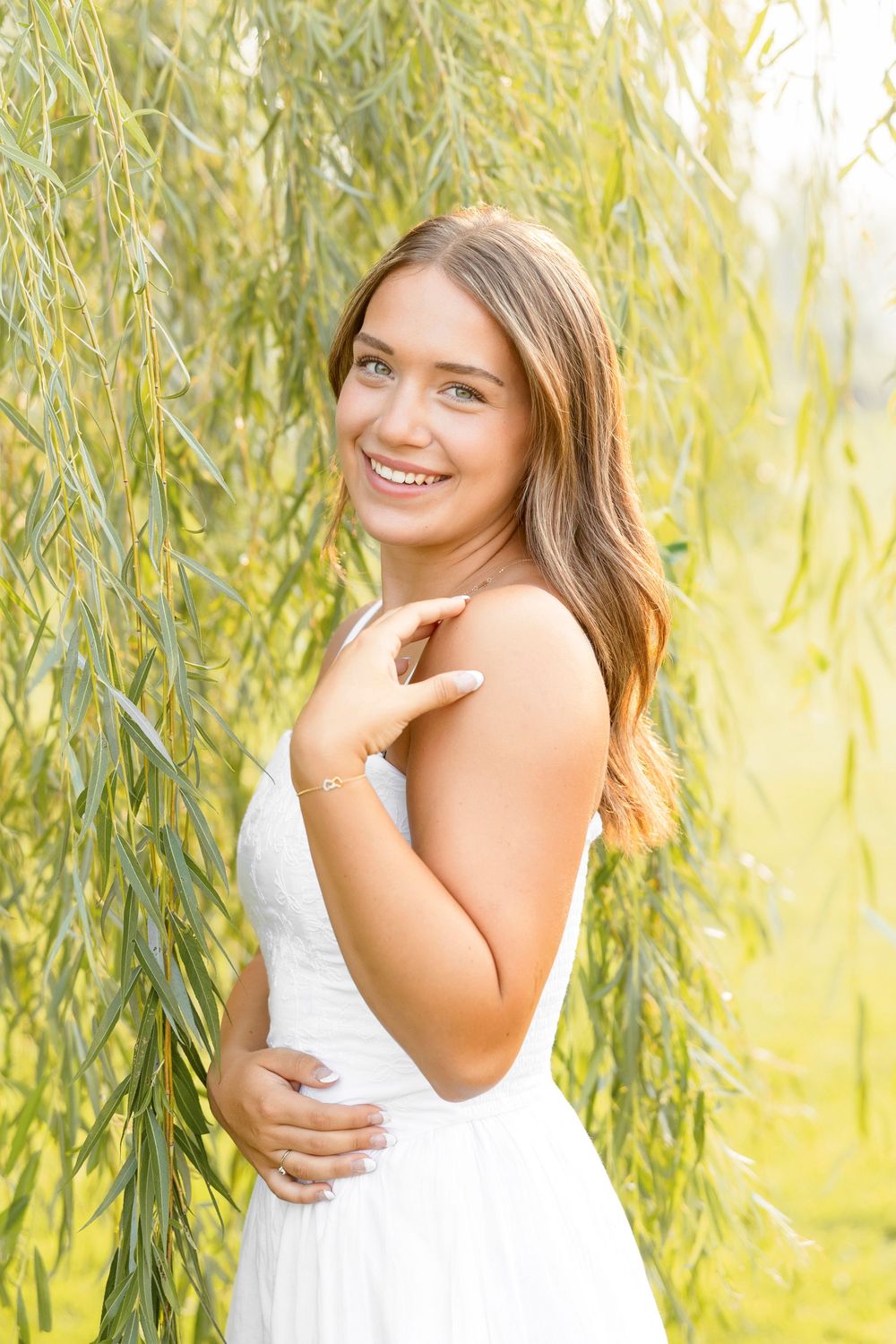 Soft portrait series against willow branches with sunlight filtering through the leaves.