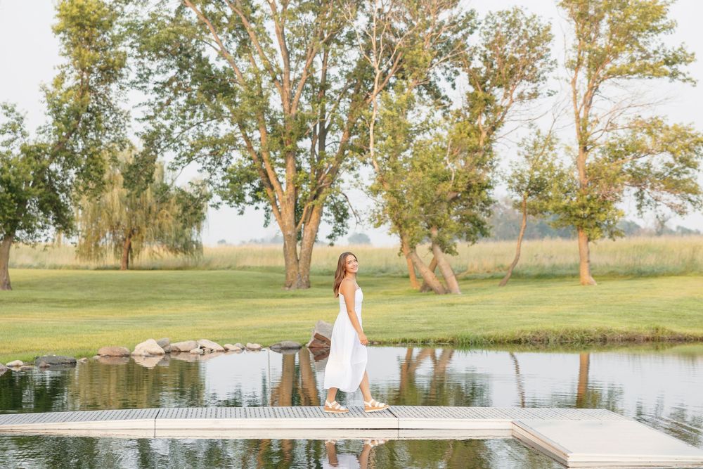 A senior poses together in a romantic lakeside senior photo session at sunset.