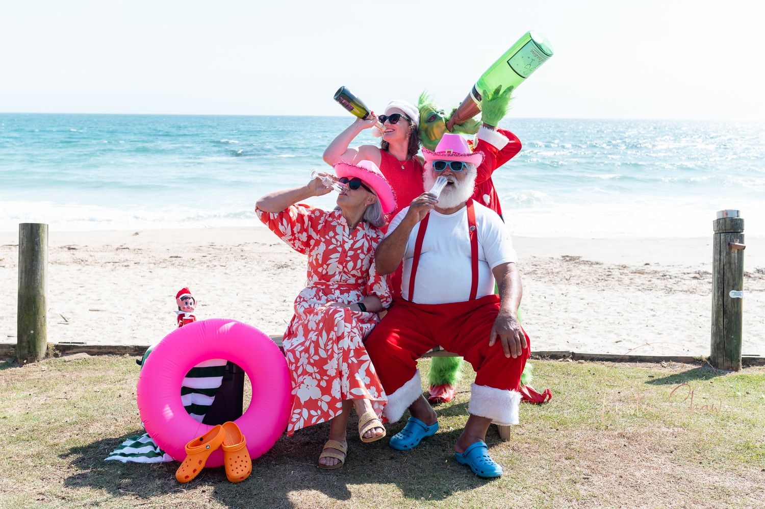 Colorful beach party scene with festive characters in costumes posing with beach toys and drinks on a sunny day.