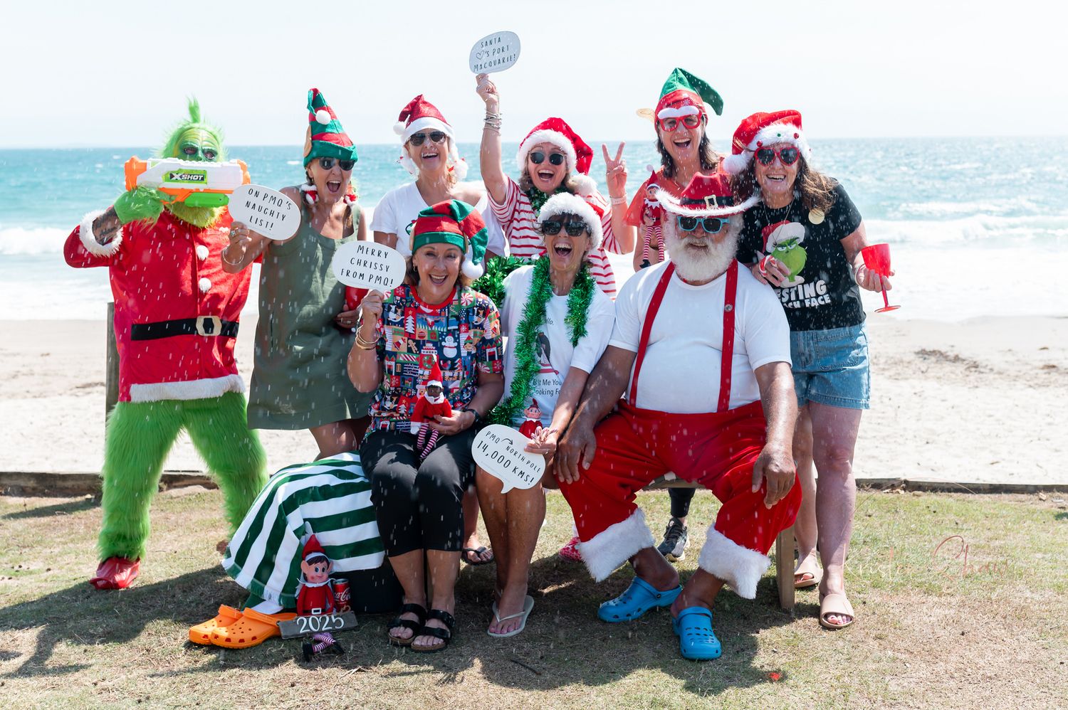 Holiday celebration at a beachside setting with people wearing Santa hats and festive costumes.