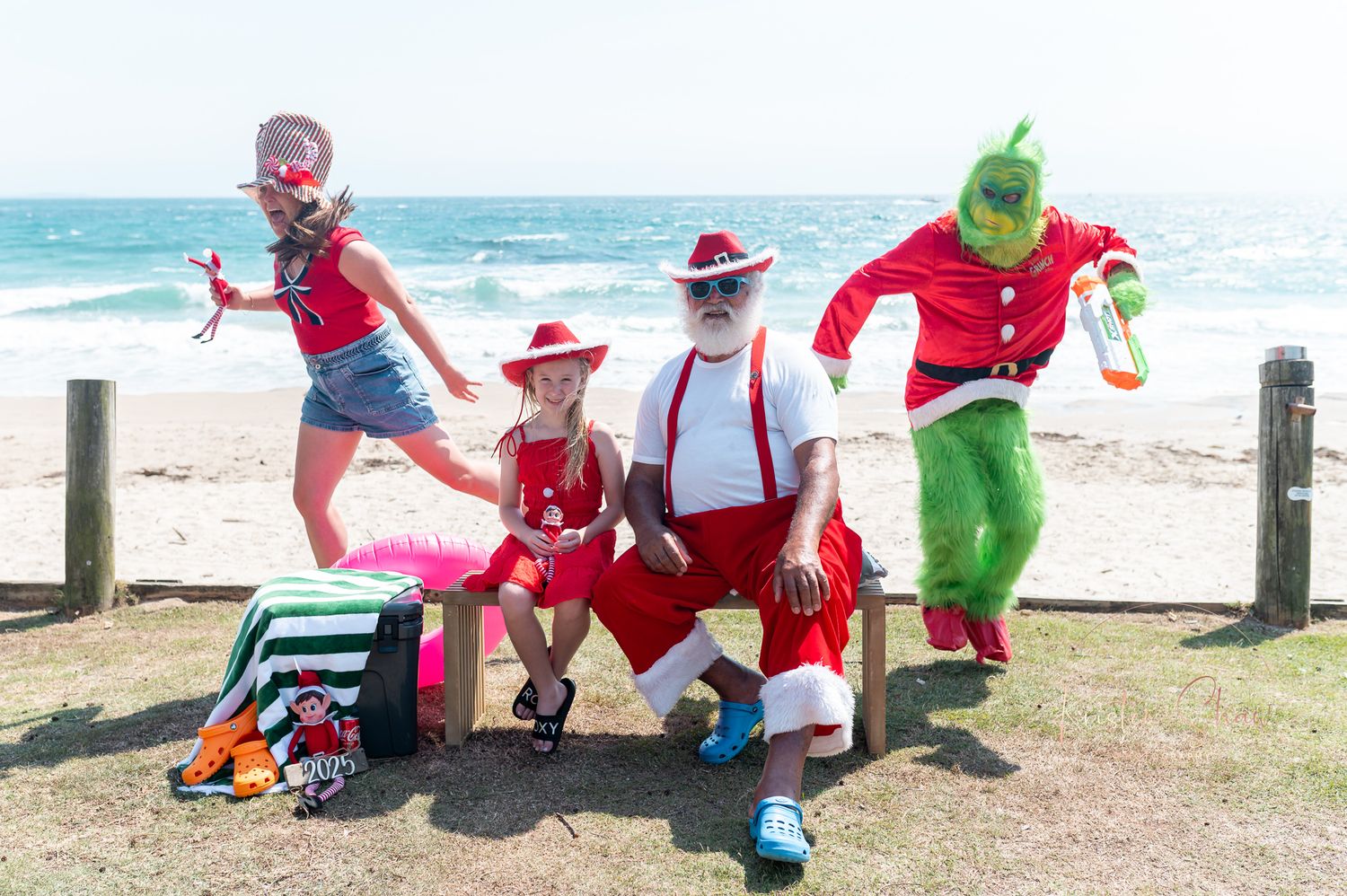 Costumed characters in festive outfits pose and interact with beachgoers along a sunny oceanfront boardwalk.