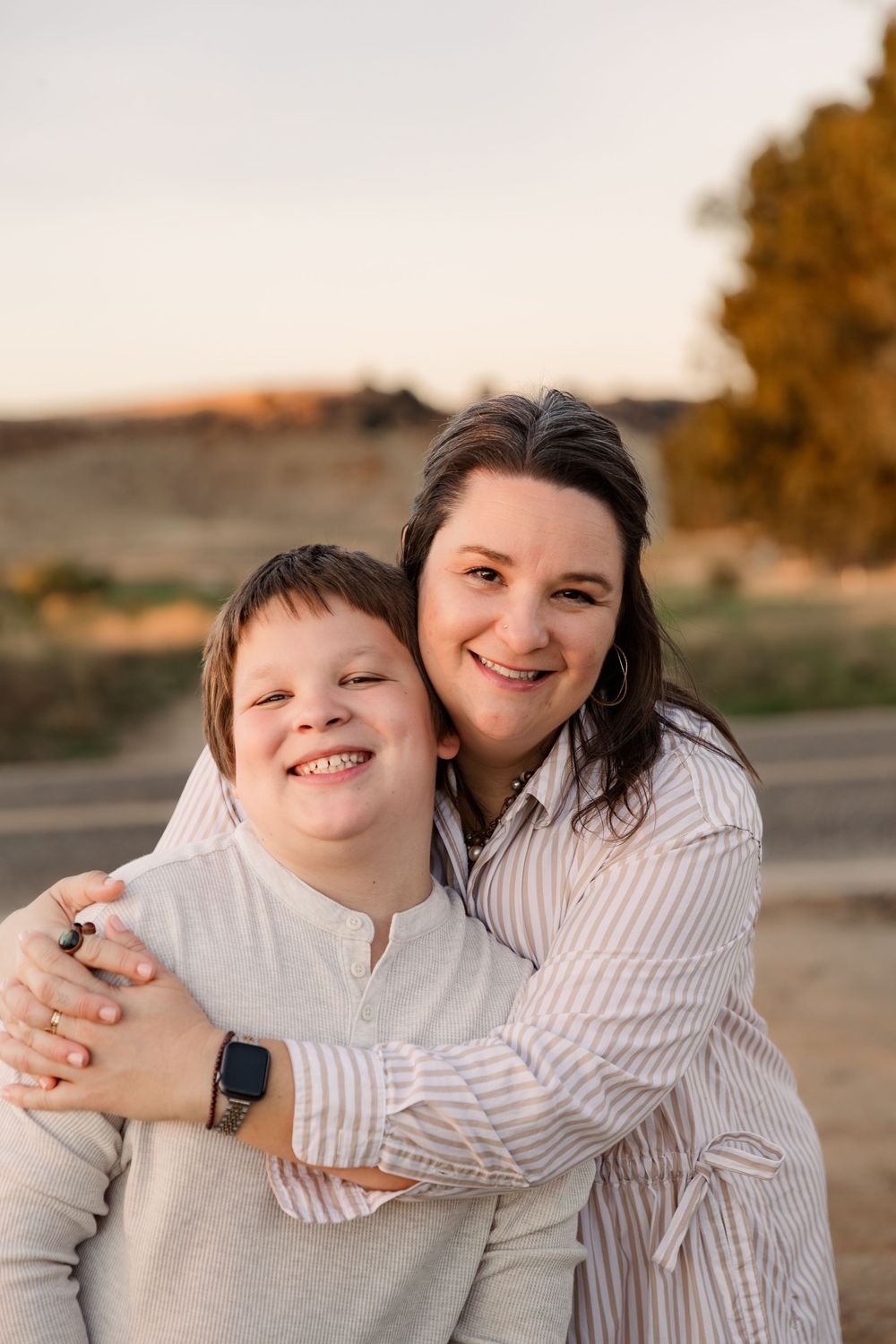A warm outdoor portrait session at sunset featuring two people embracing and smiling together.