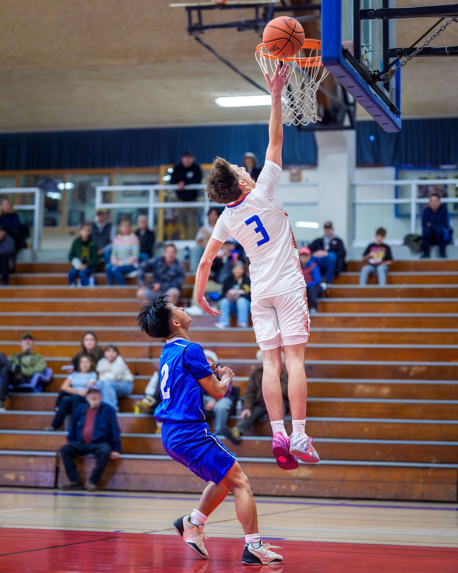 Basketball players compete for possession during an intense game in a high school gymnasium.