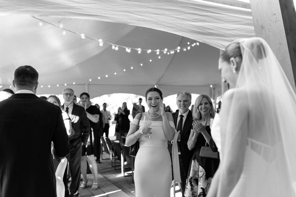Wedding guests dance and celebrate under a tent with string lights at an elegant reception.
