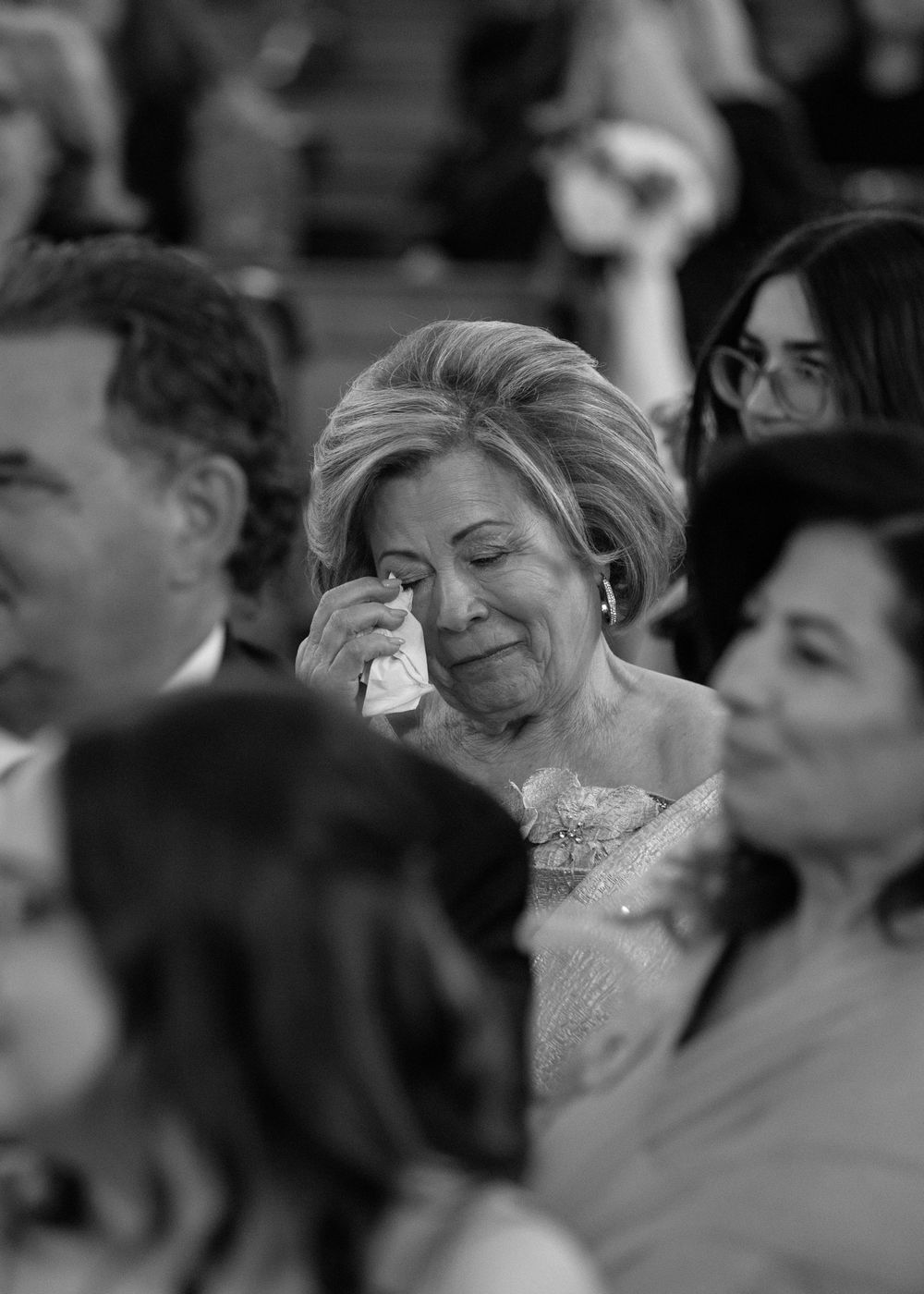 Black and white candid shot of emotional wedding ceremony guests in their seats.