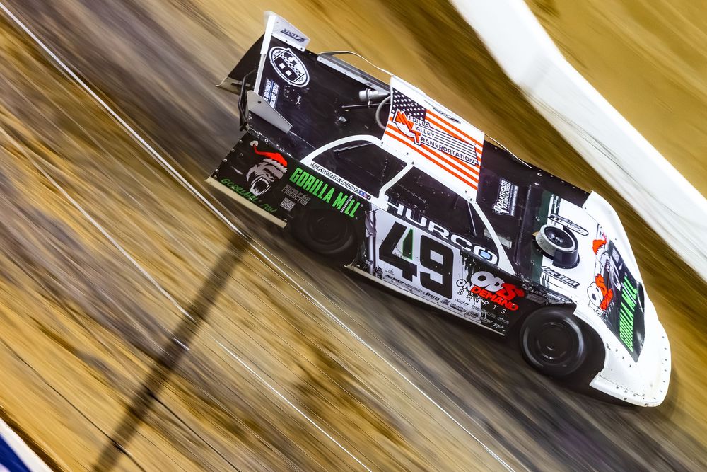 A black and white NASCAR race car with the number 43 speeds past with motion blur on a track.