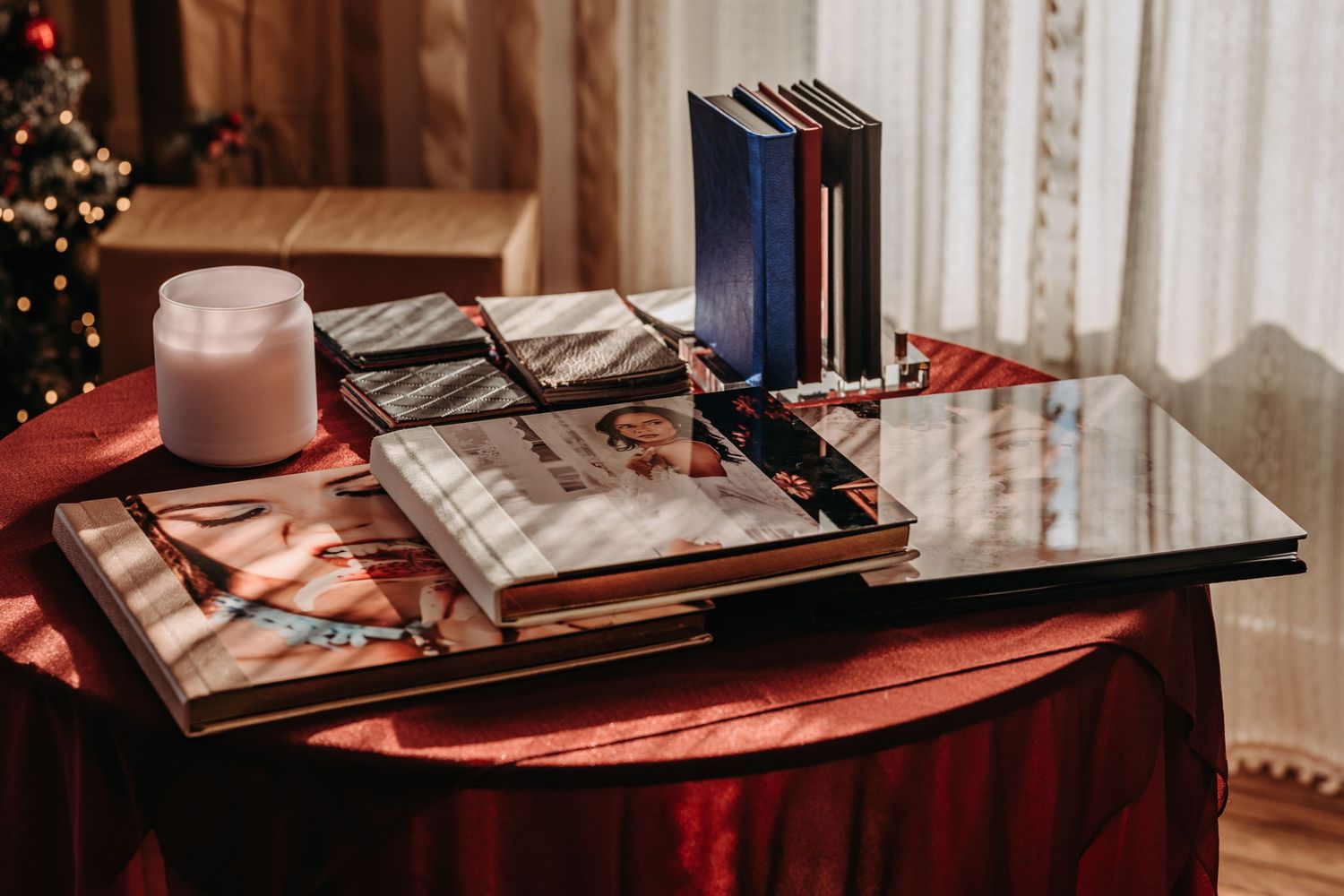 Books, notebooks and a pink mug arranged on a glass table with red tablecloth in cozy interior setting.