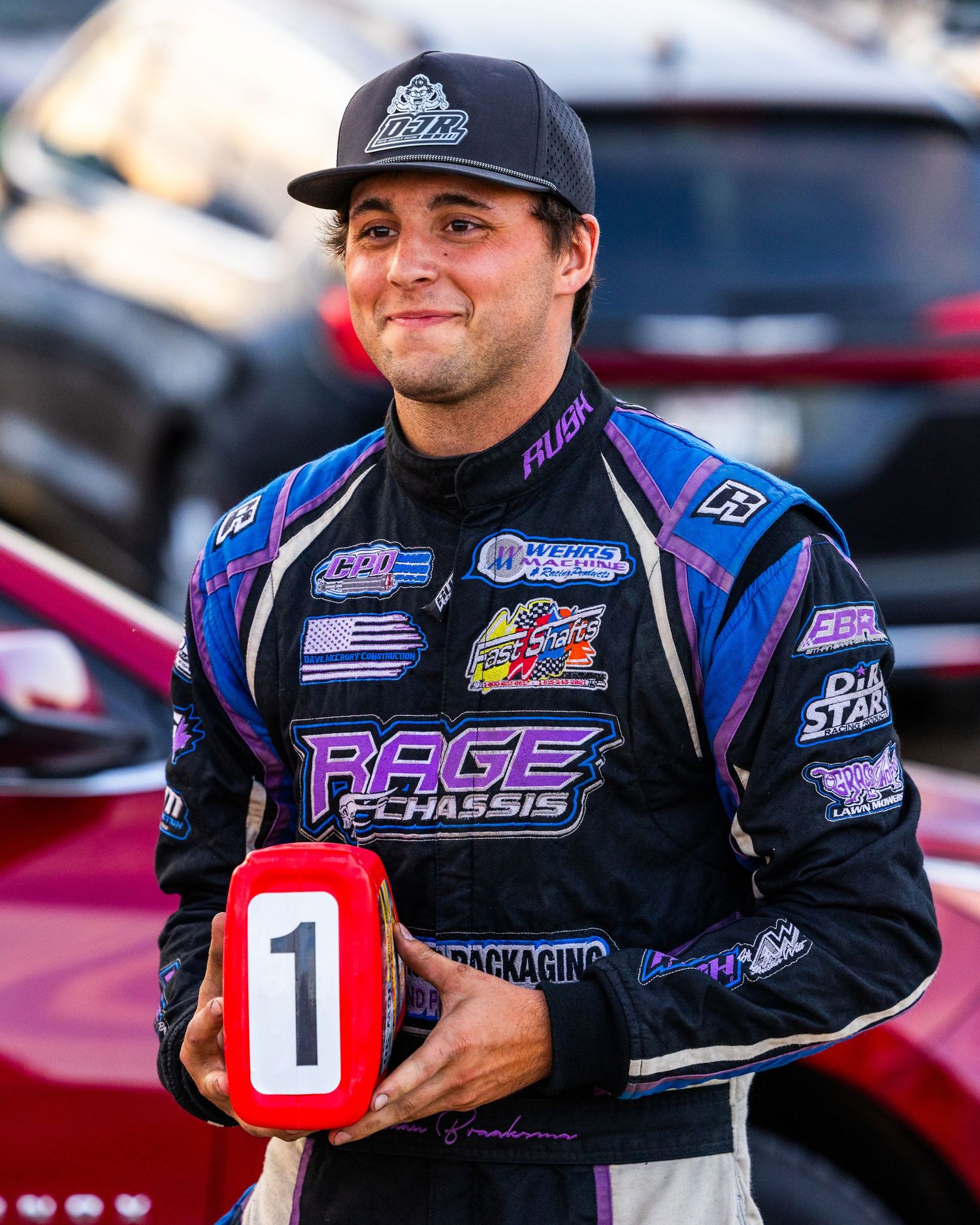 A racing driver celebrates victory by waving a checkered flag at night after a race.
