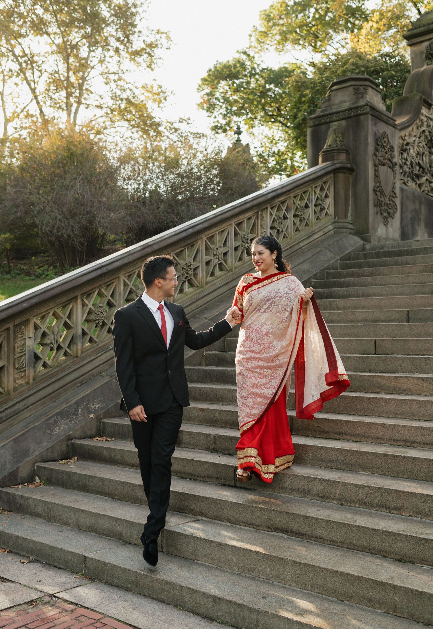 Couple ascending ornate stone staircase in traditional formal attire.