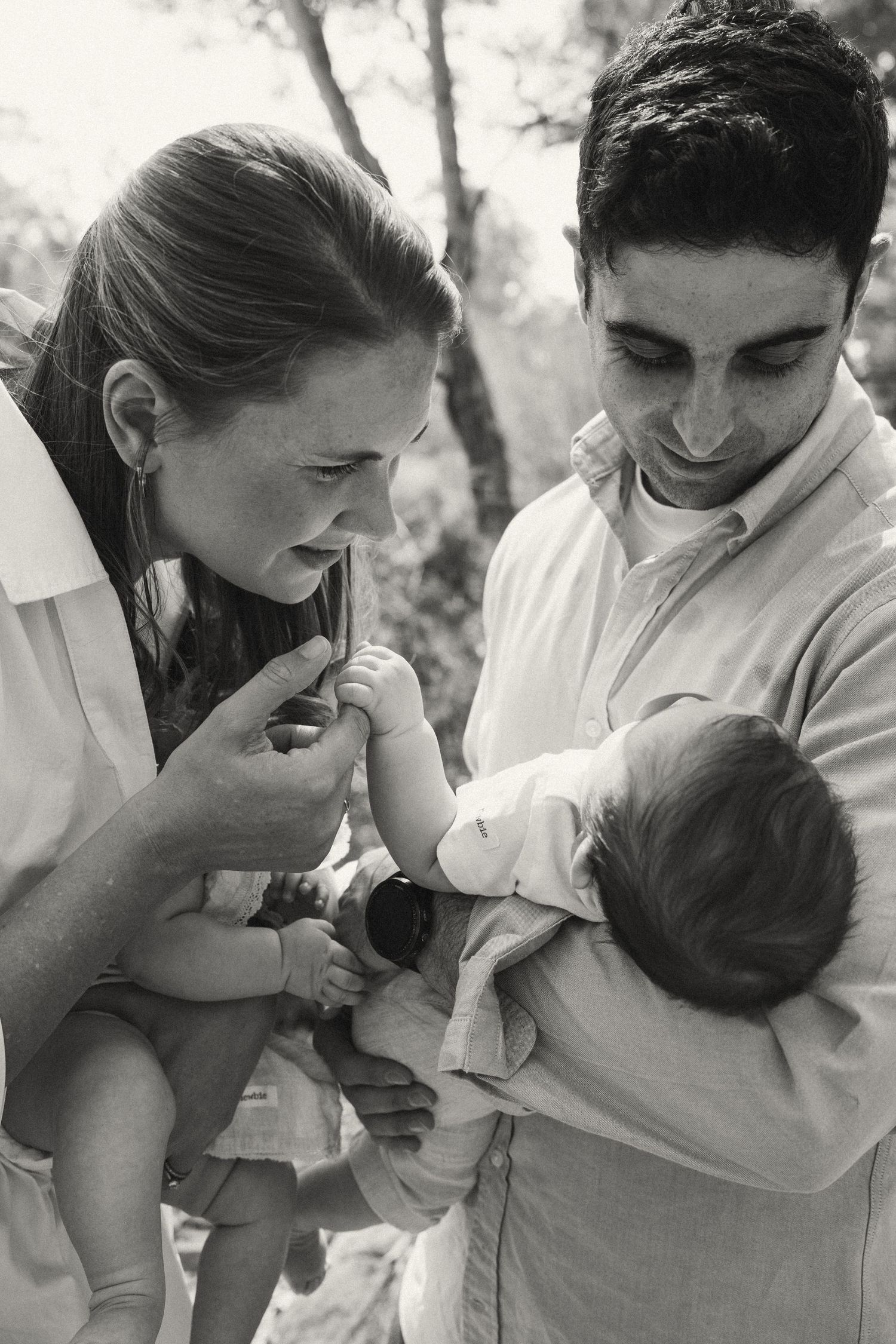 Black and white photo series of parents lovingly bonding with their infant in natural light.