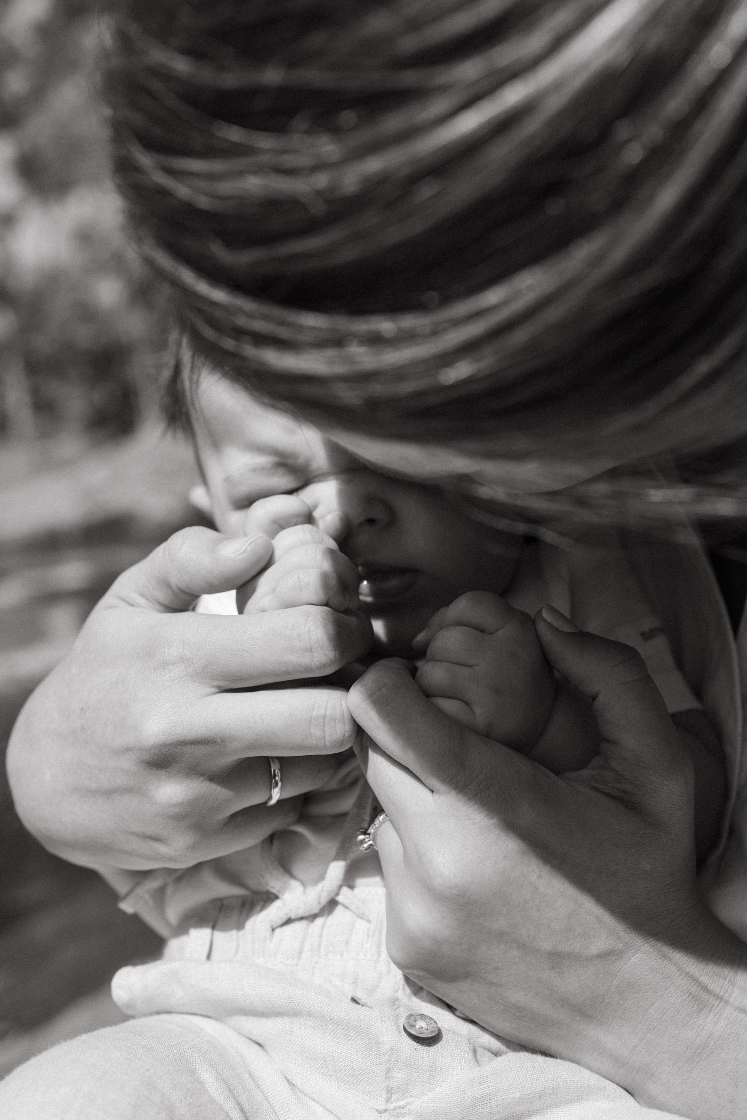 Artistic black and white close-up of gentle hands cradling a small face.