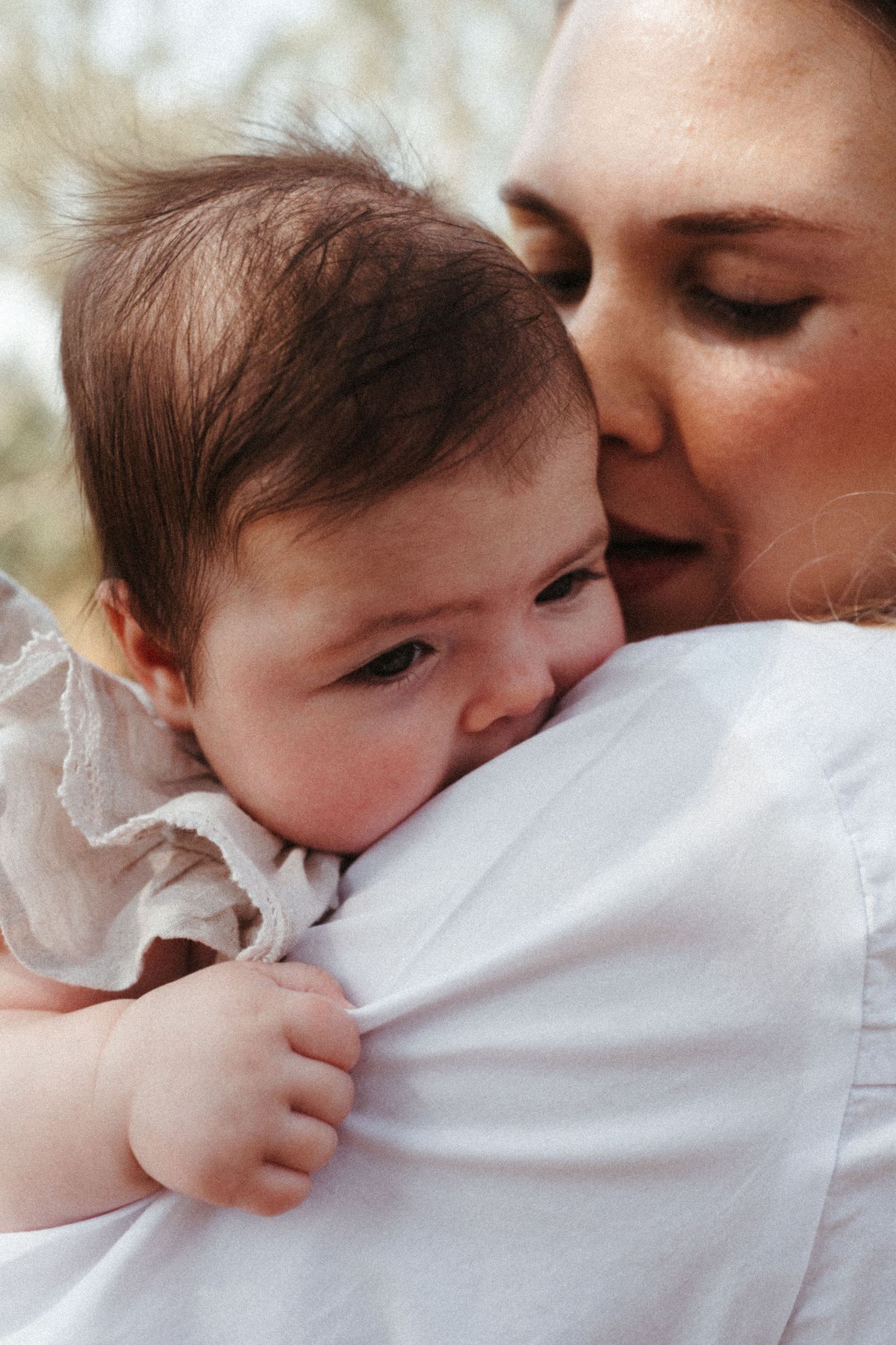 Close-up series of intimate cuddles between parent and infant in white.