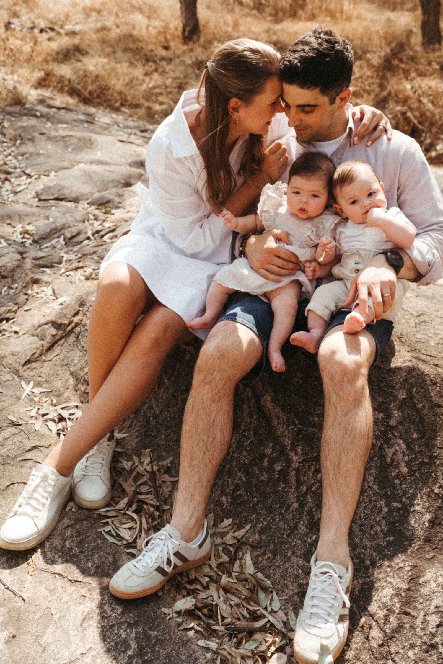 Family sitting together on a rocky outcrop sharing intimate moments in casual attire.