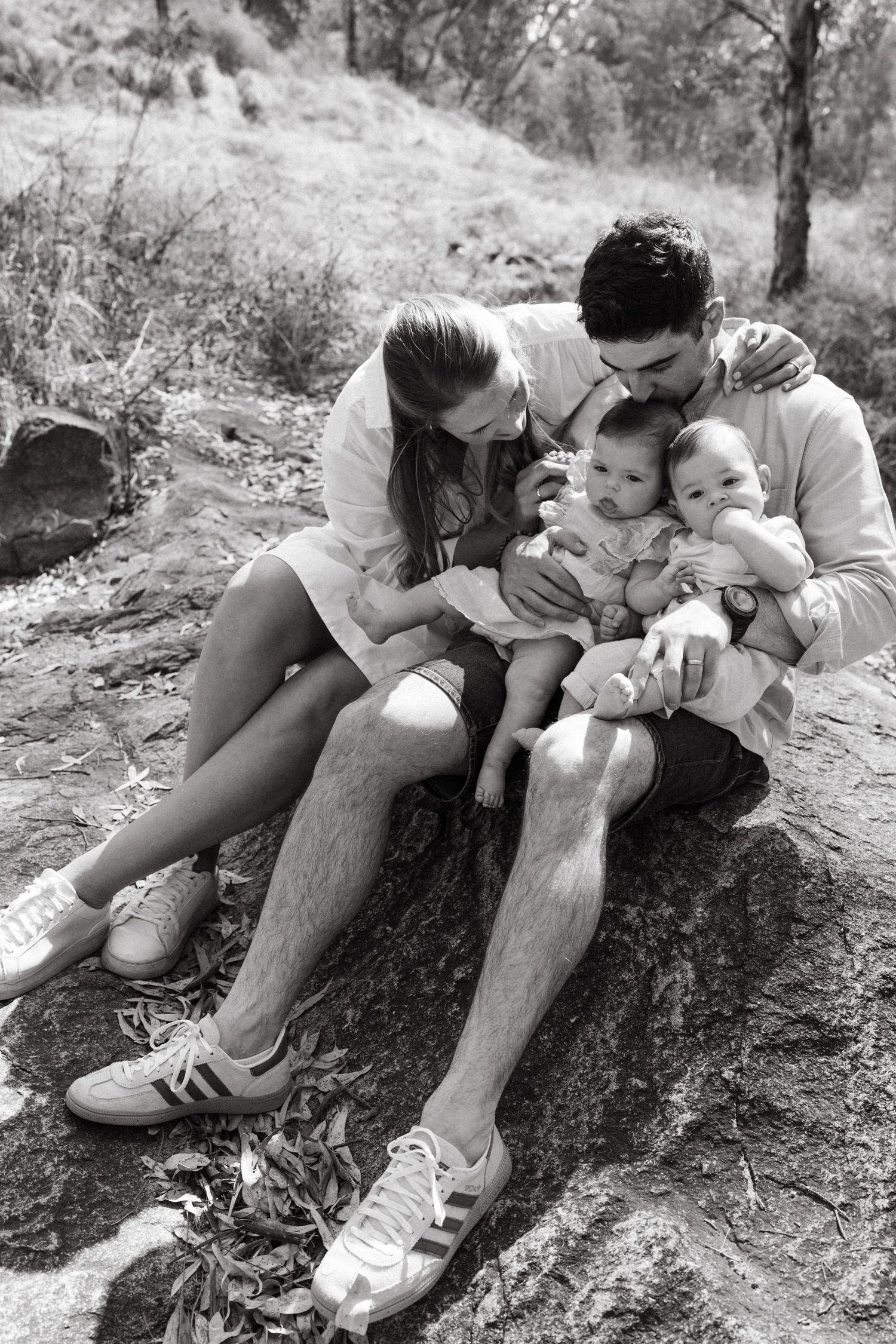 Black and white series of family cuddling together on a natural stone surface.