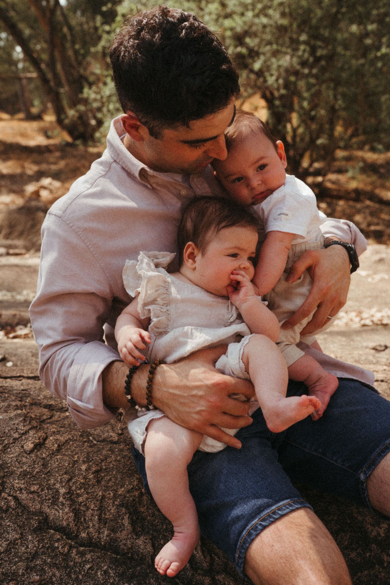Intimate family moments captured on a rocky surface in natural lighting.