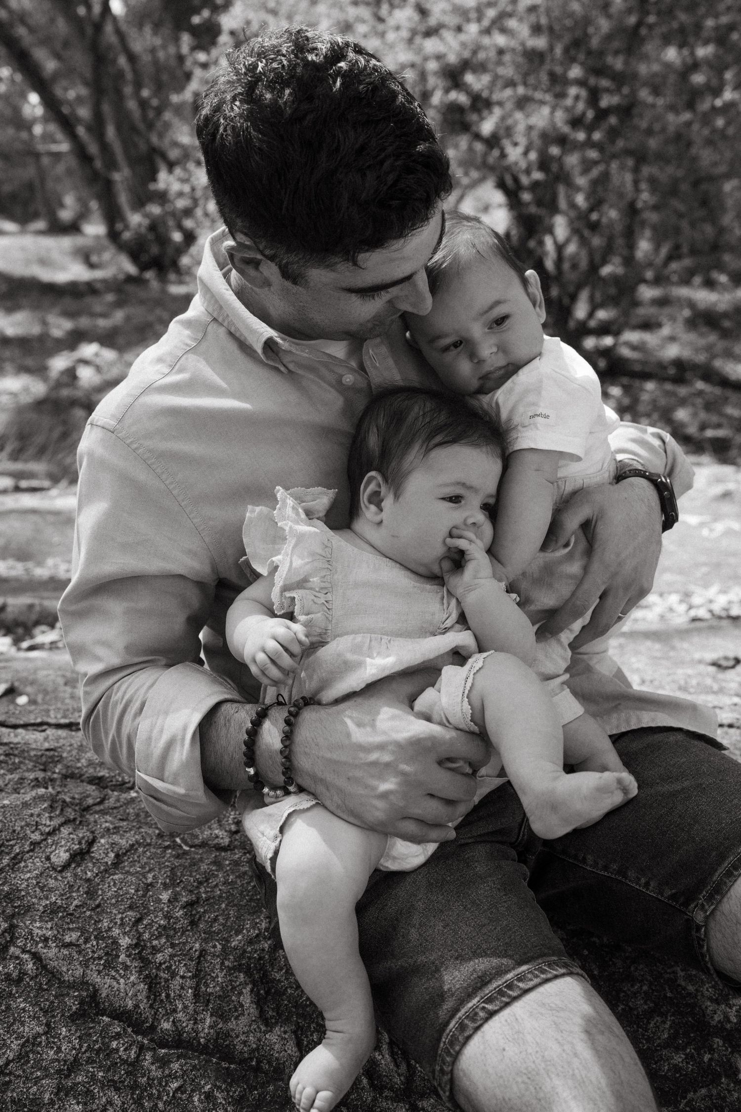 Black and white series showing tender family embraces on outdoor stone seating.