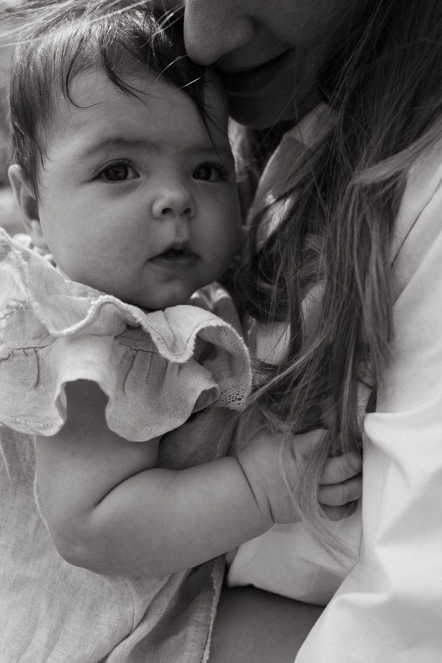 Baby wearing white lace collar during intimate family photoshoot.