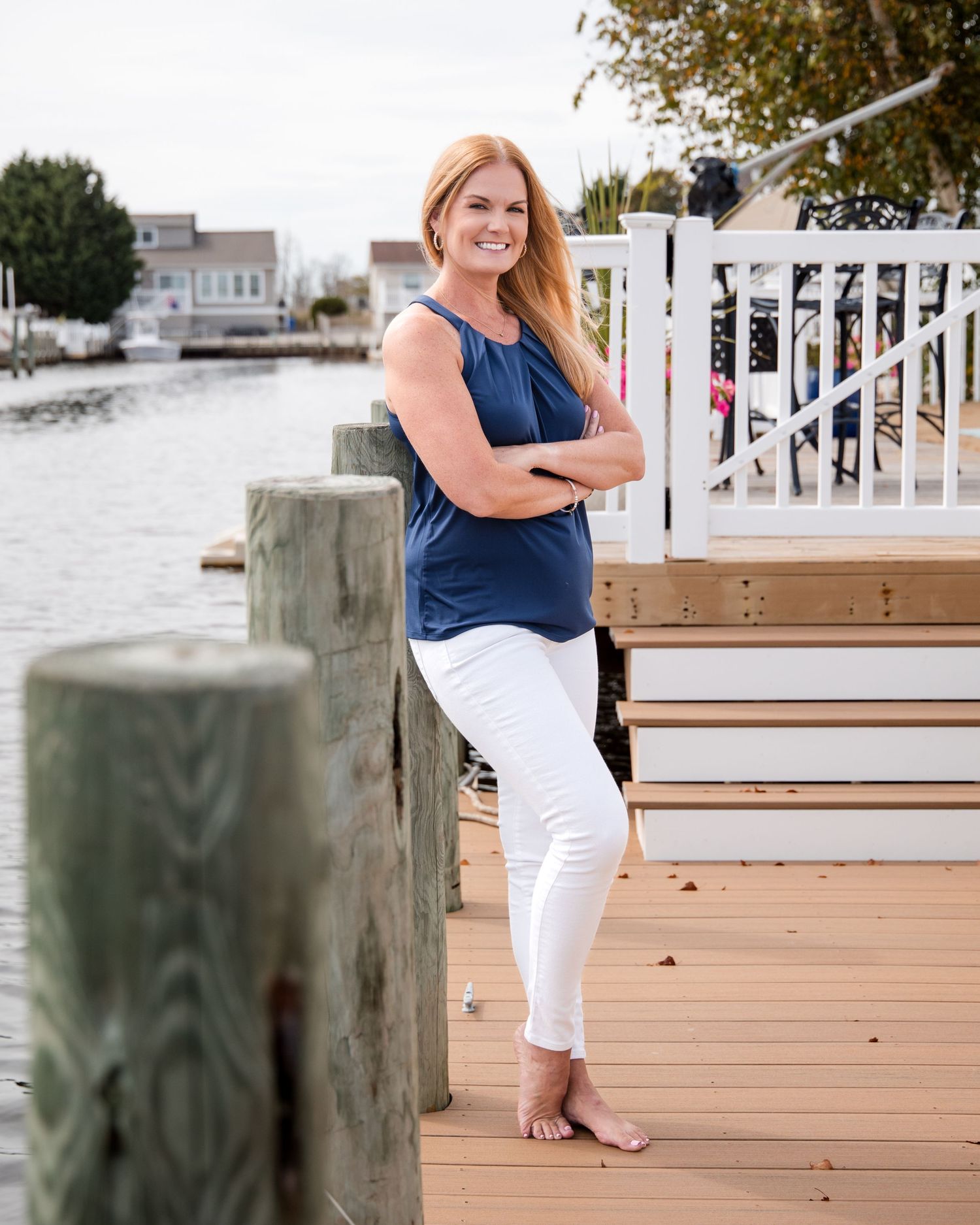Branding client Lauren Hornacek standing outside on her dock, arms crossed, smiling at camera.