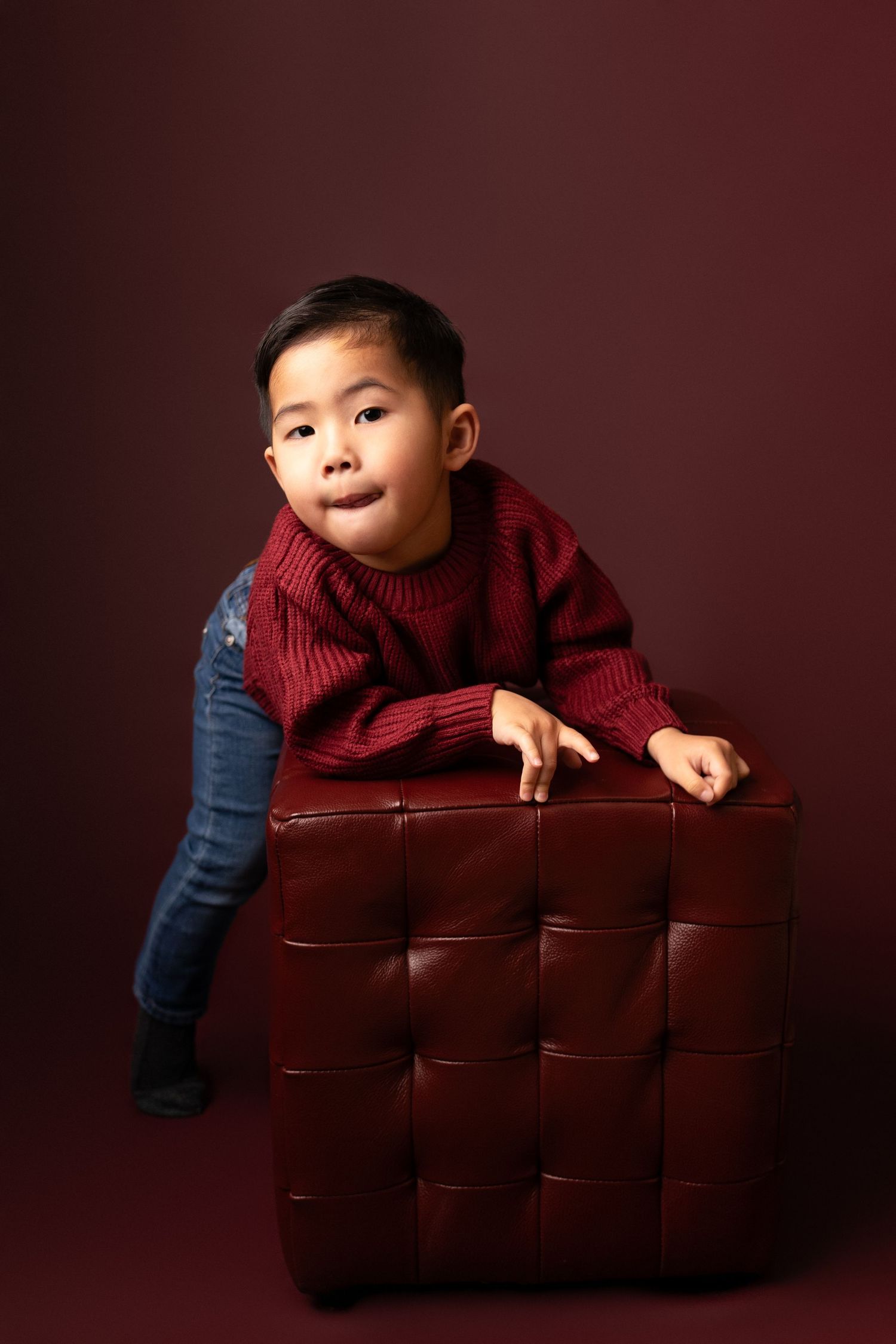 Creative poses with burgundy cushions against a deep red background.
