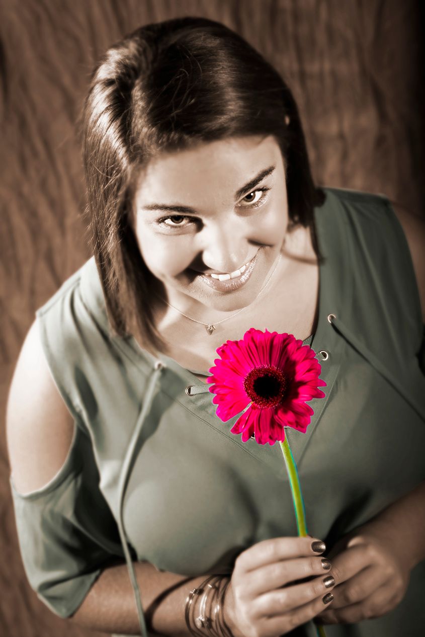 Portrait with bright pink gerbera daisy flower against brown background in selective color style. (Mumford New York)