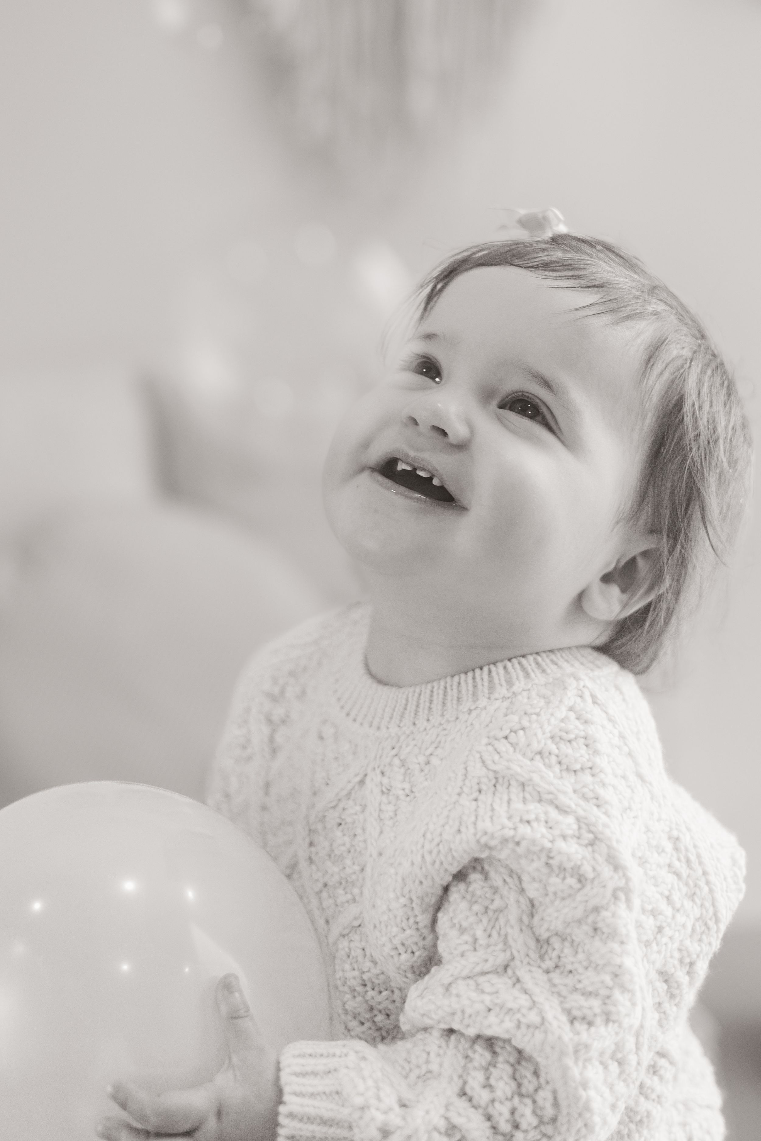toddler smiling up at balloons during studio milestone session in Bishopdale, Christchurch