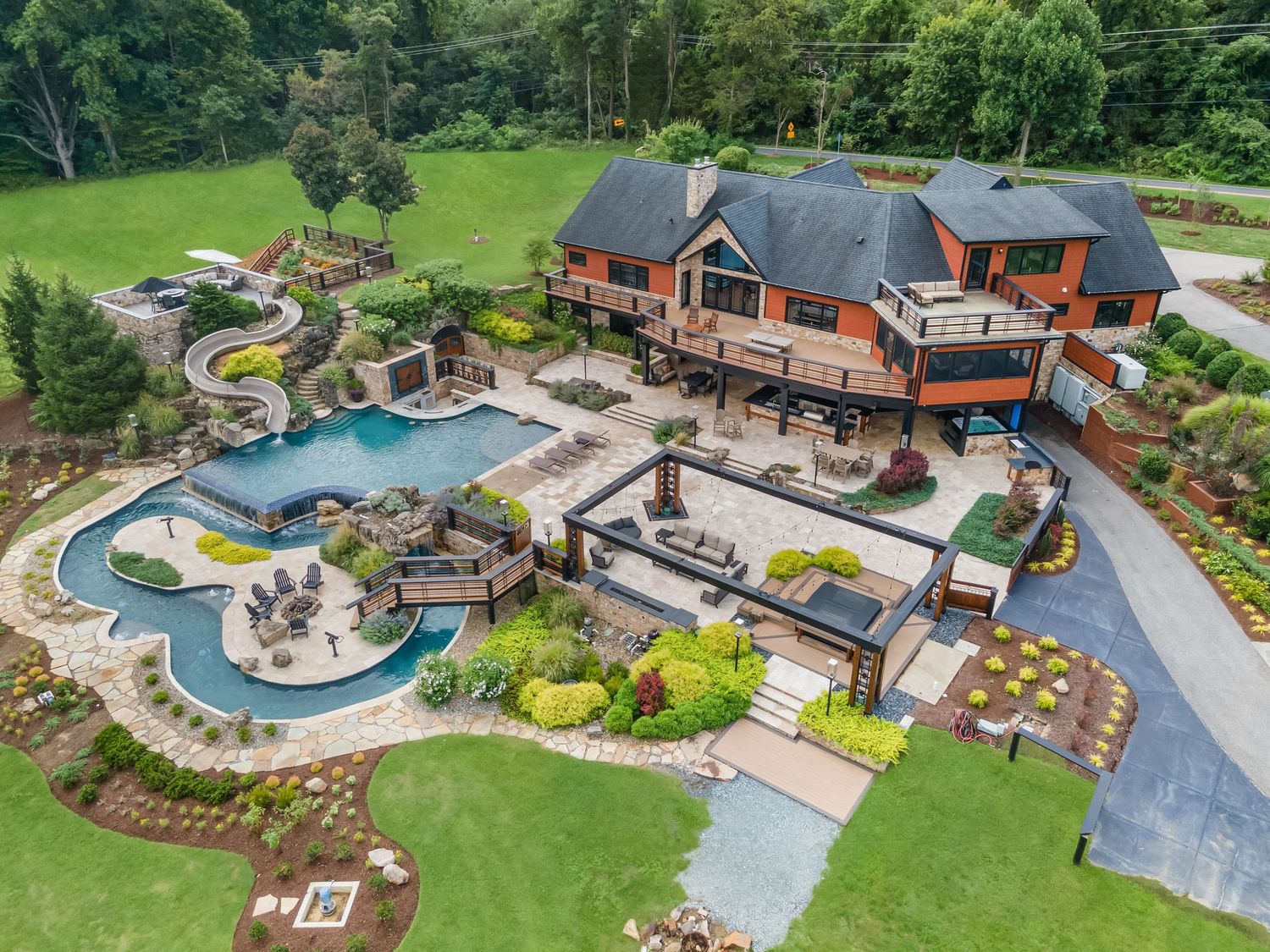Panoramic drone shot of an estate property with elaborate pool, patio areas and manicured grounds.