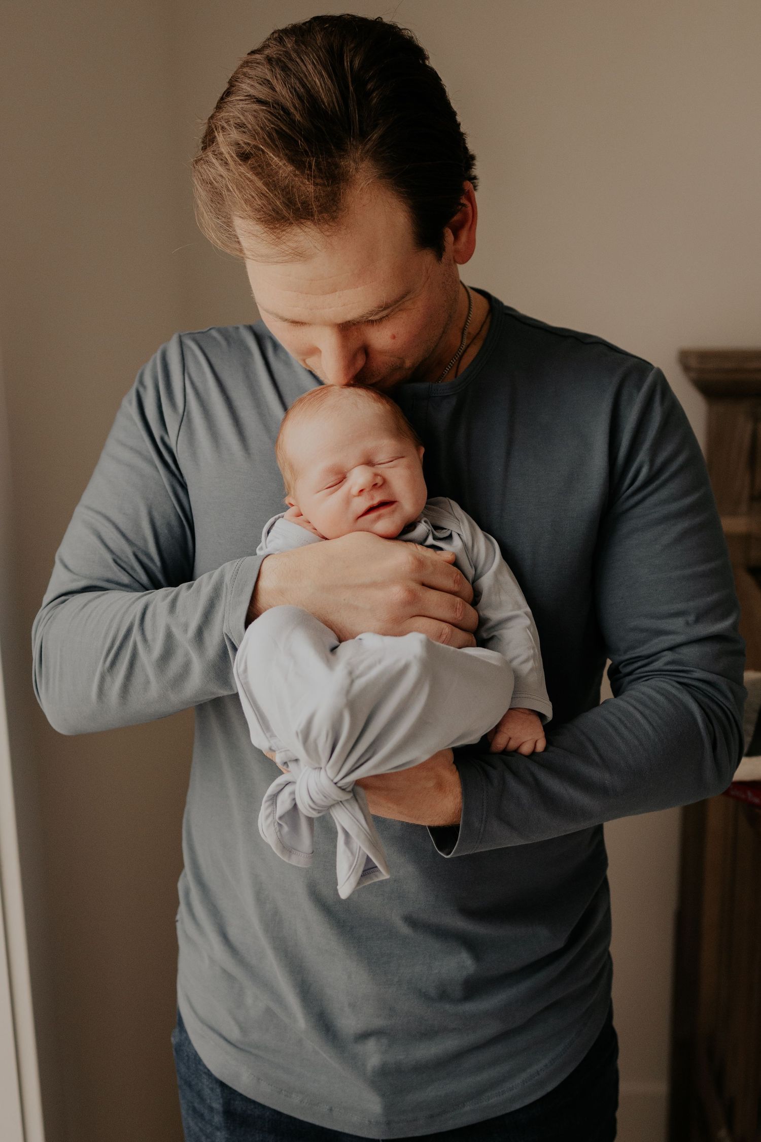 A tender moment between dad and newborn baby as they cuddle during lifestyle newborn photography session in Minneapolis.