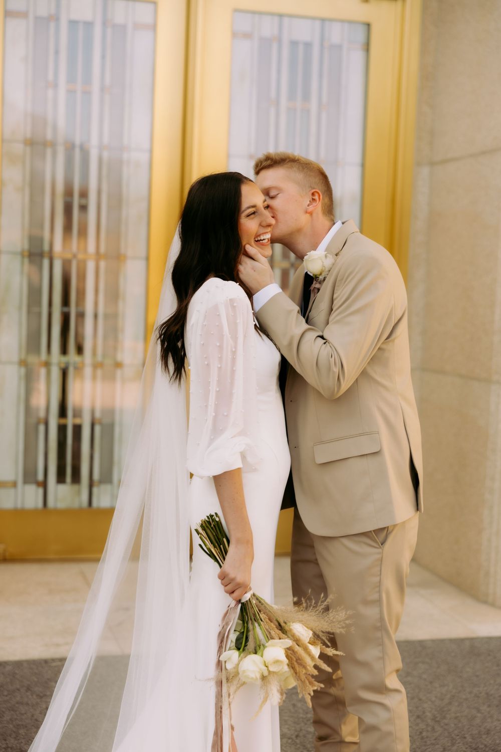 Intimate wedding moment captured in front of elegant gold doors.