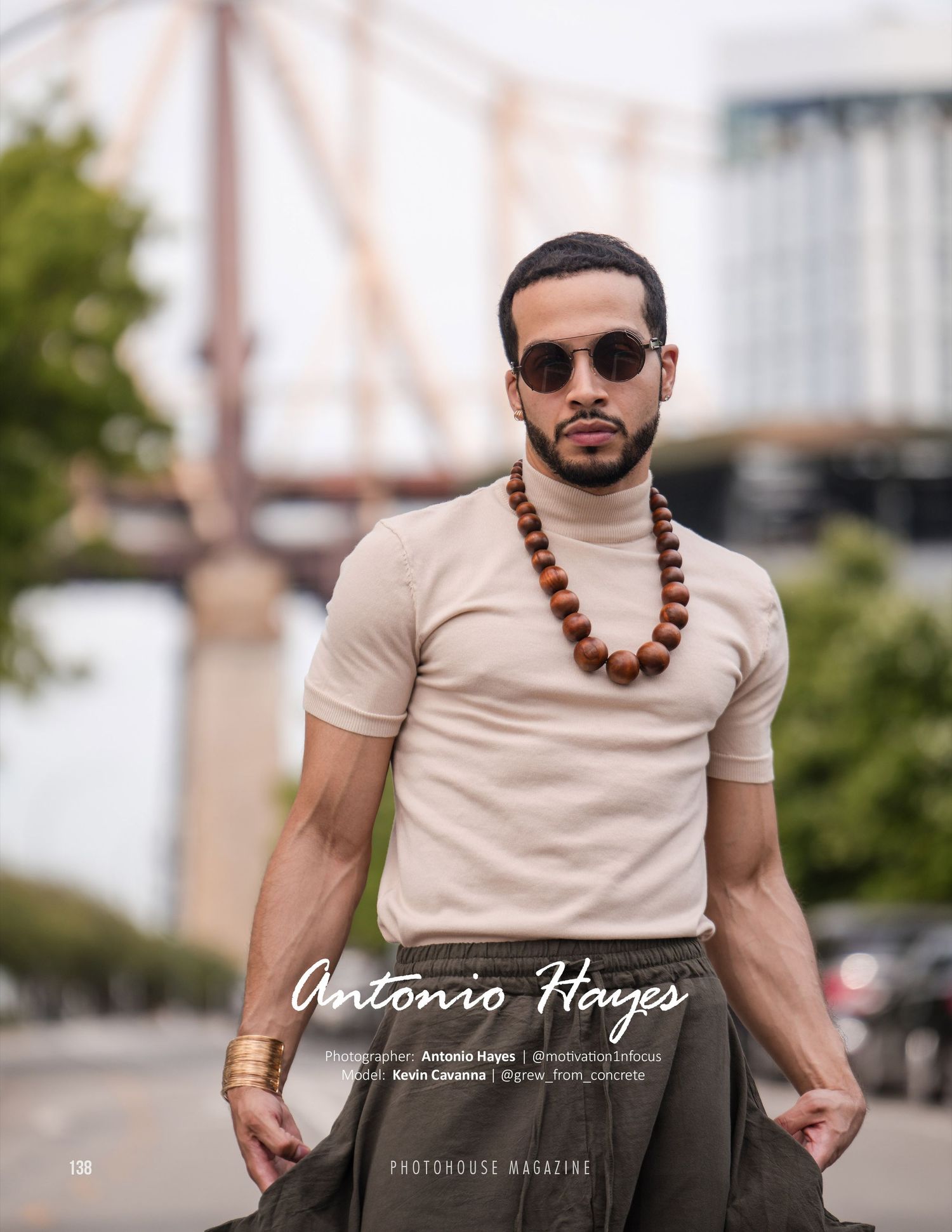 Stylish fashion photo featuring beige turtleneck and wooden bead necklace against urban bridge backdrop.