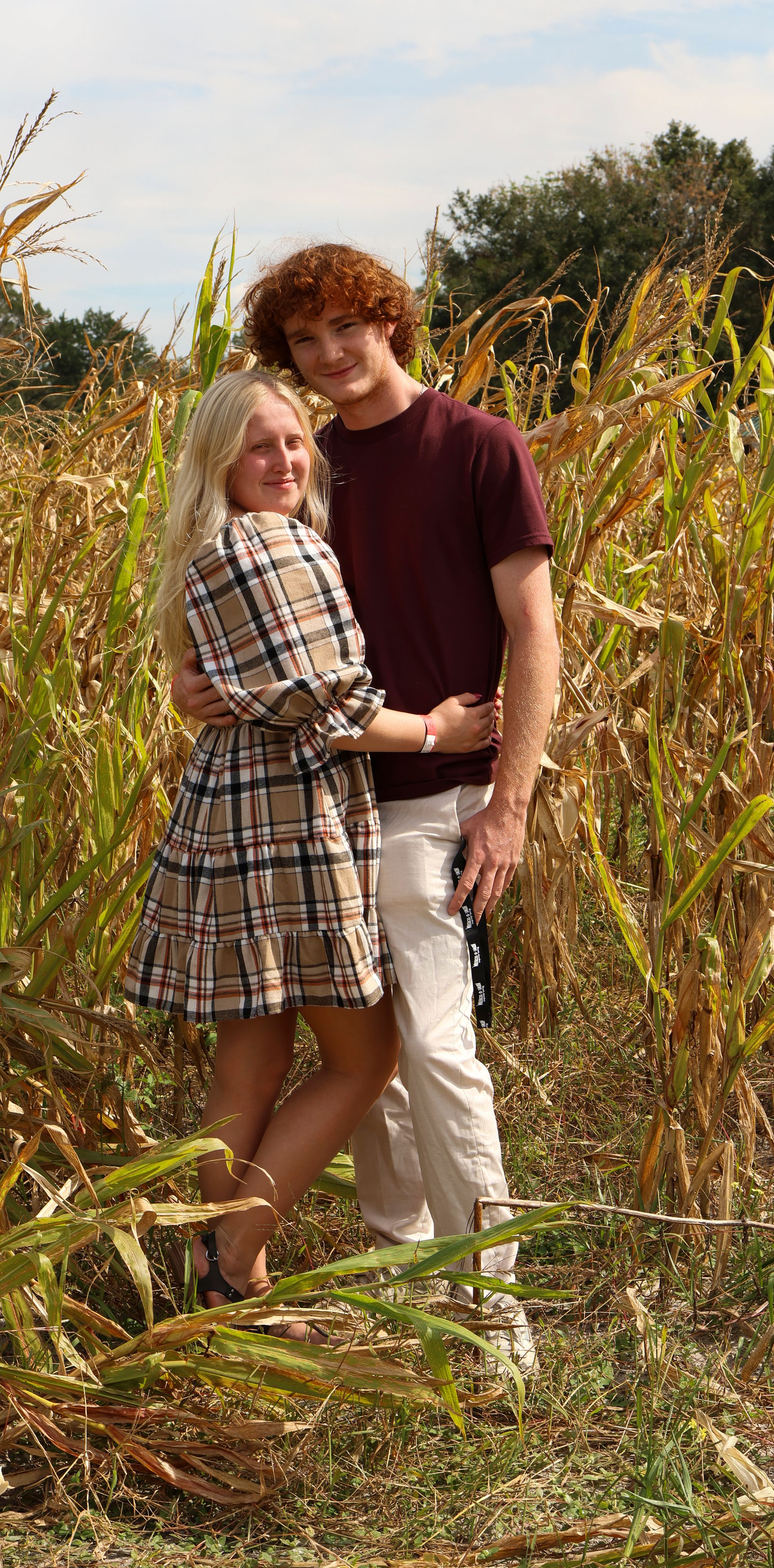 A couple shares a romantic moment together in a cornfield during autumn.
