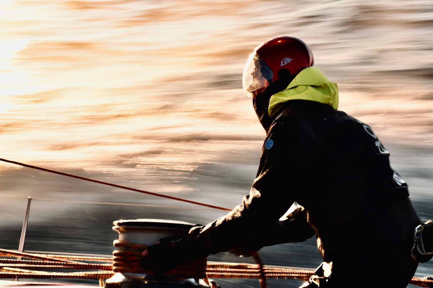Sailors working on deck during sunset with dramatic lighting.