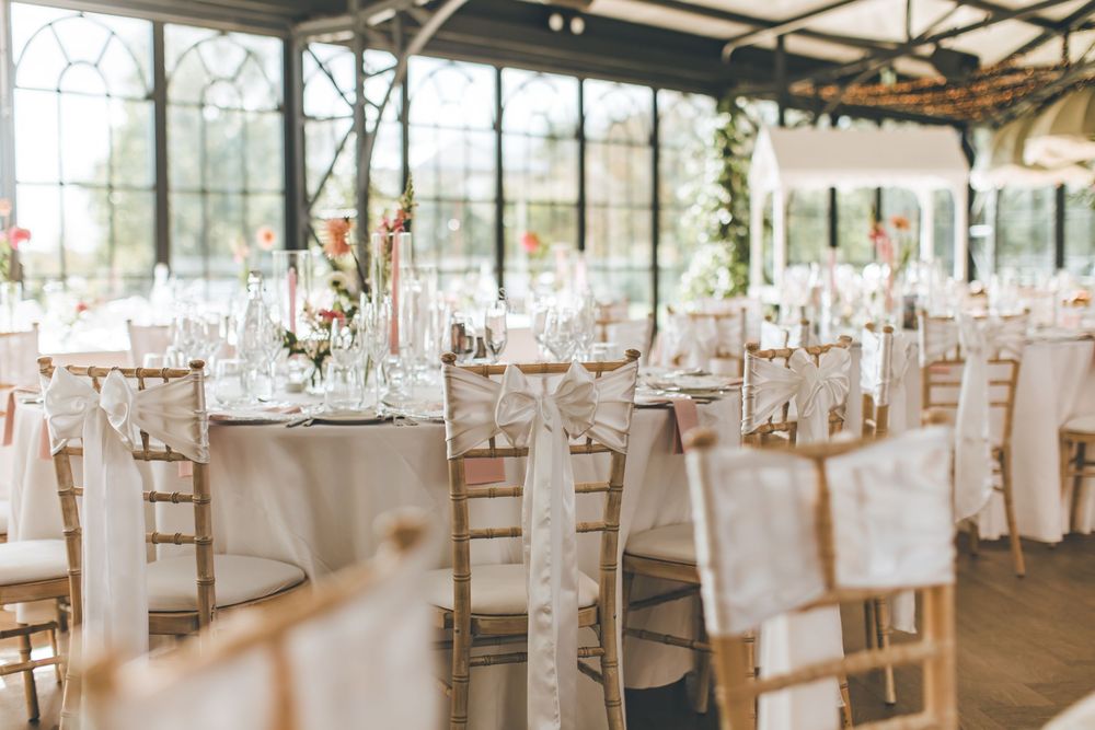 Elegant wedding reception venue with white table settings and floor-to-ceiling windows.
