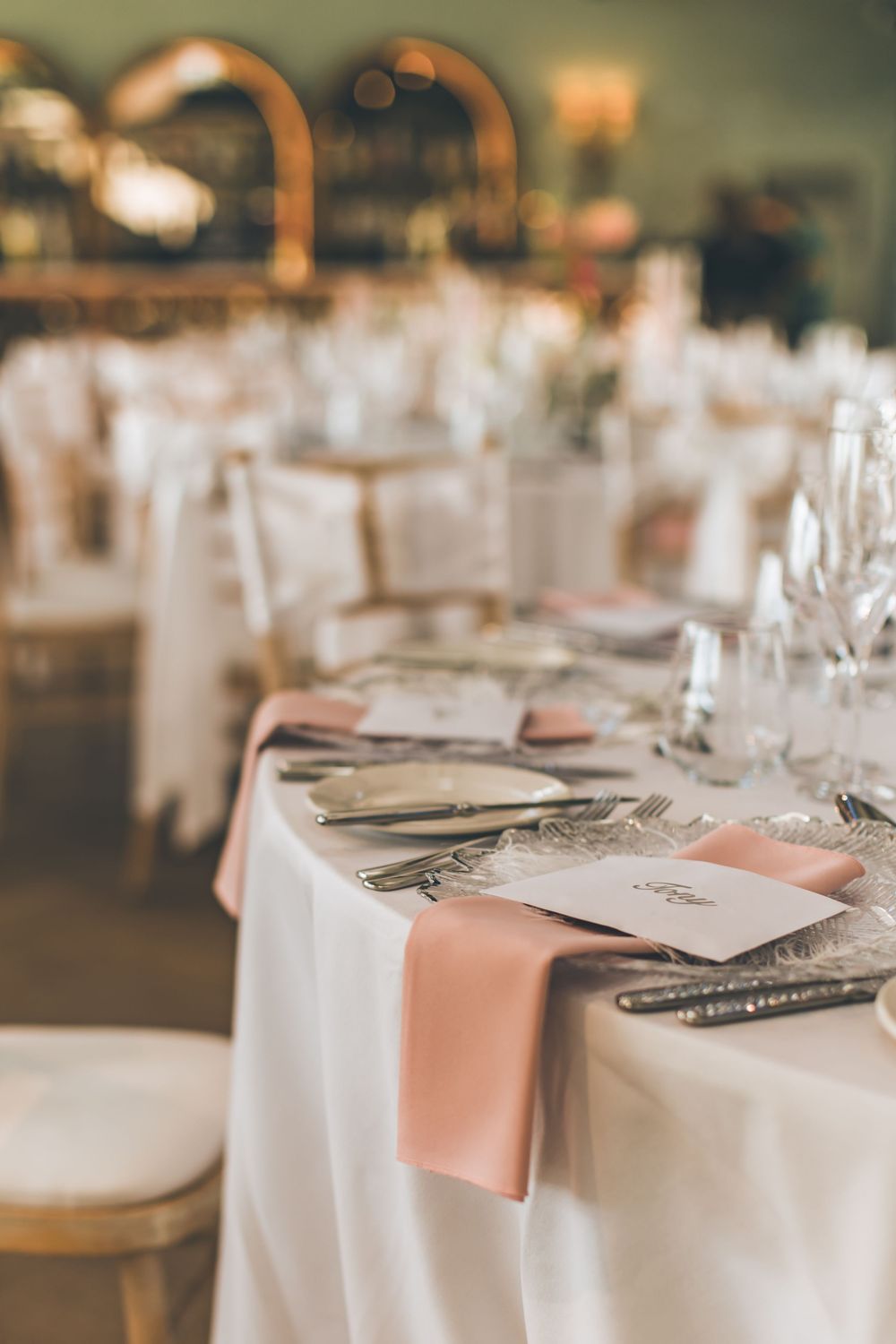 Elegant wedding reception table setting with peach napkins and white linens.