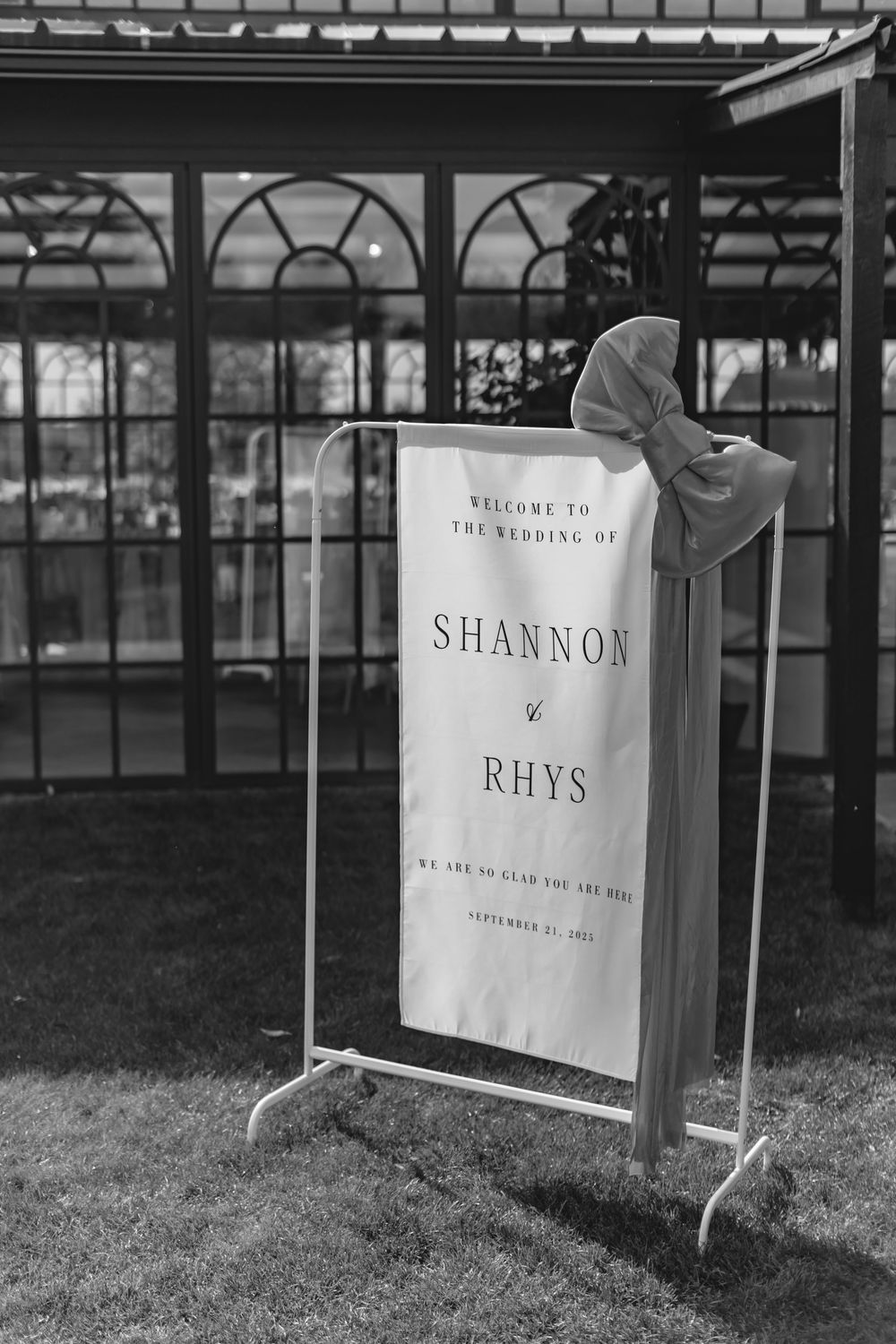 Black and white welcome sign for Shannon and Rhys wedding with decorative bow.