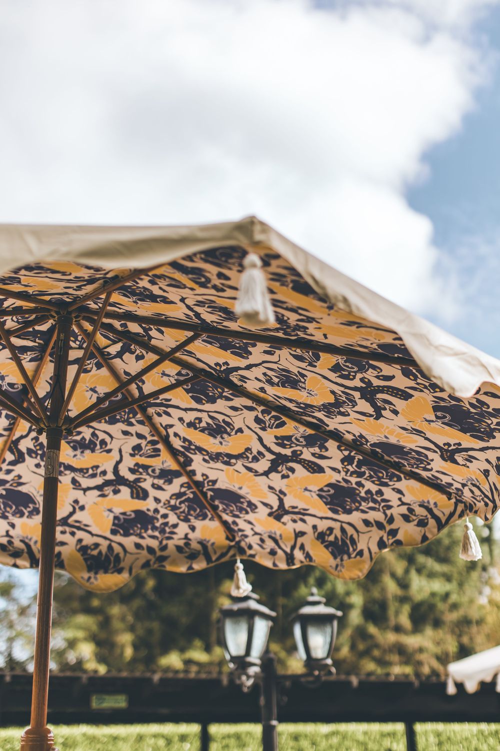Decorative patio umbrellas with intricate black floral patterns against a sunny sky.