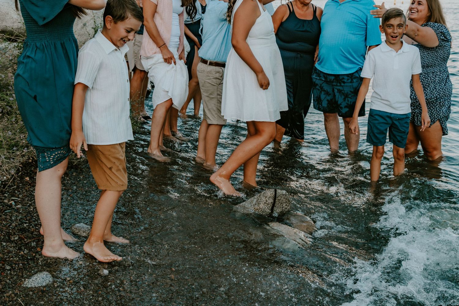 A group of people standing in shallow ocean water at a beach gathering.