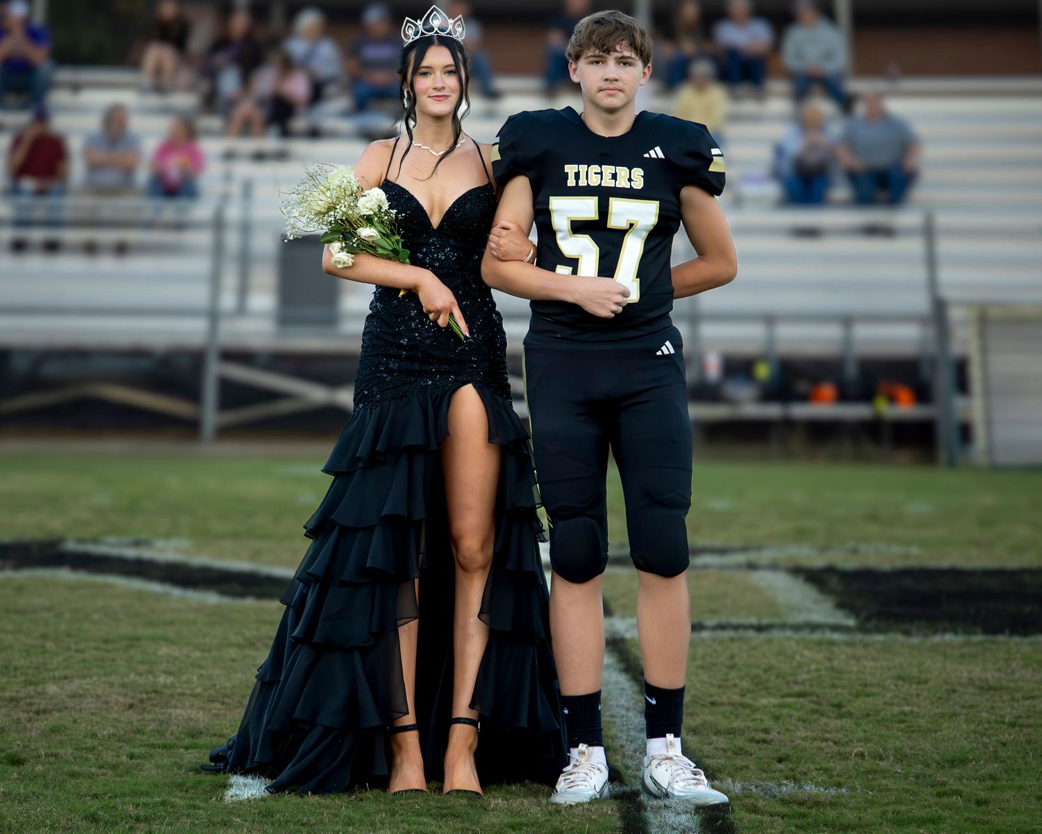 Football players in black uniforms stand on a grass field during a game or practice session.