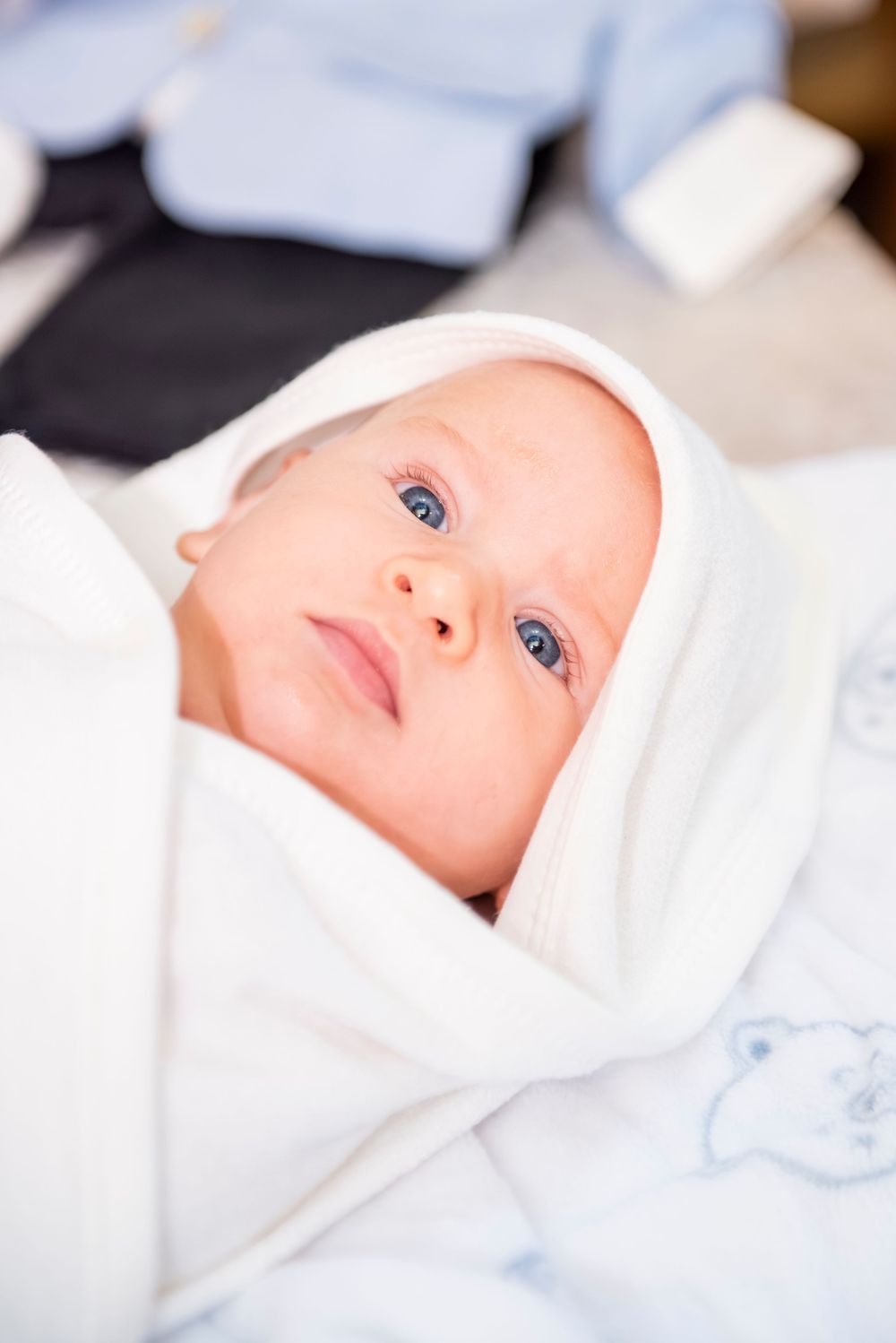 Close-up portraits of an infant wearing white against a soft blurred background.