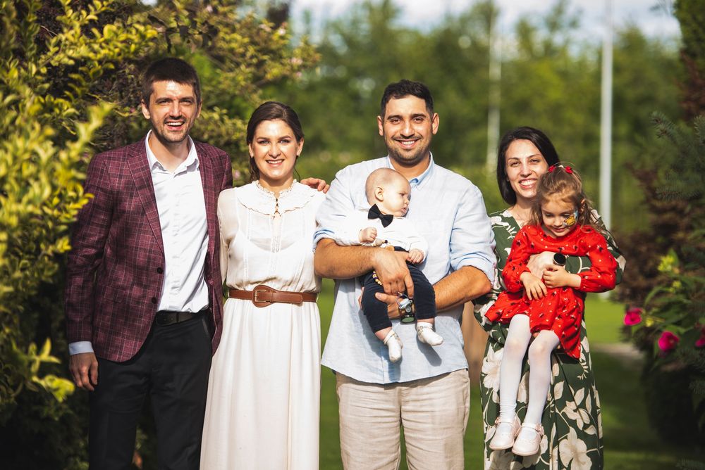 Family and guests gathered outdoors for celebration photos in a garden setting.