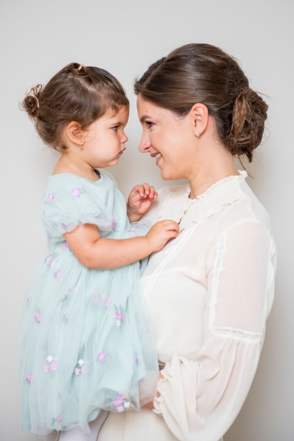 Sweet interaction between parent and child in matching light outfits captured in a series of tender moments.