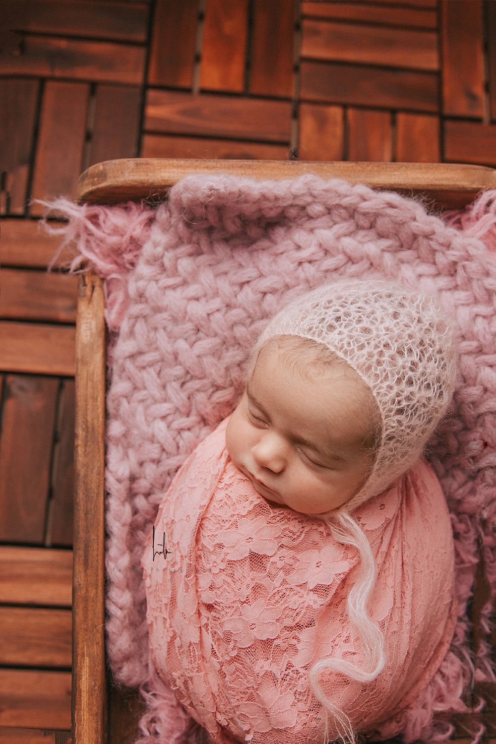 Newborn photography series showing baby wrapped in pink lace against rustic wooden background.