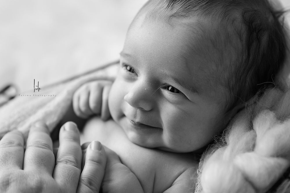 Sleeping infant in white lace bonnet photographed in black and white with soft lighting.
