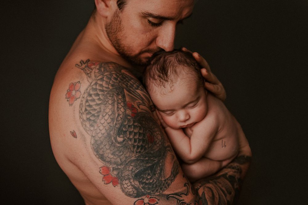 A sequence of intimate black and white photos showing a tattooed parent tenderly holding and bonding with a baby.