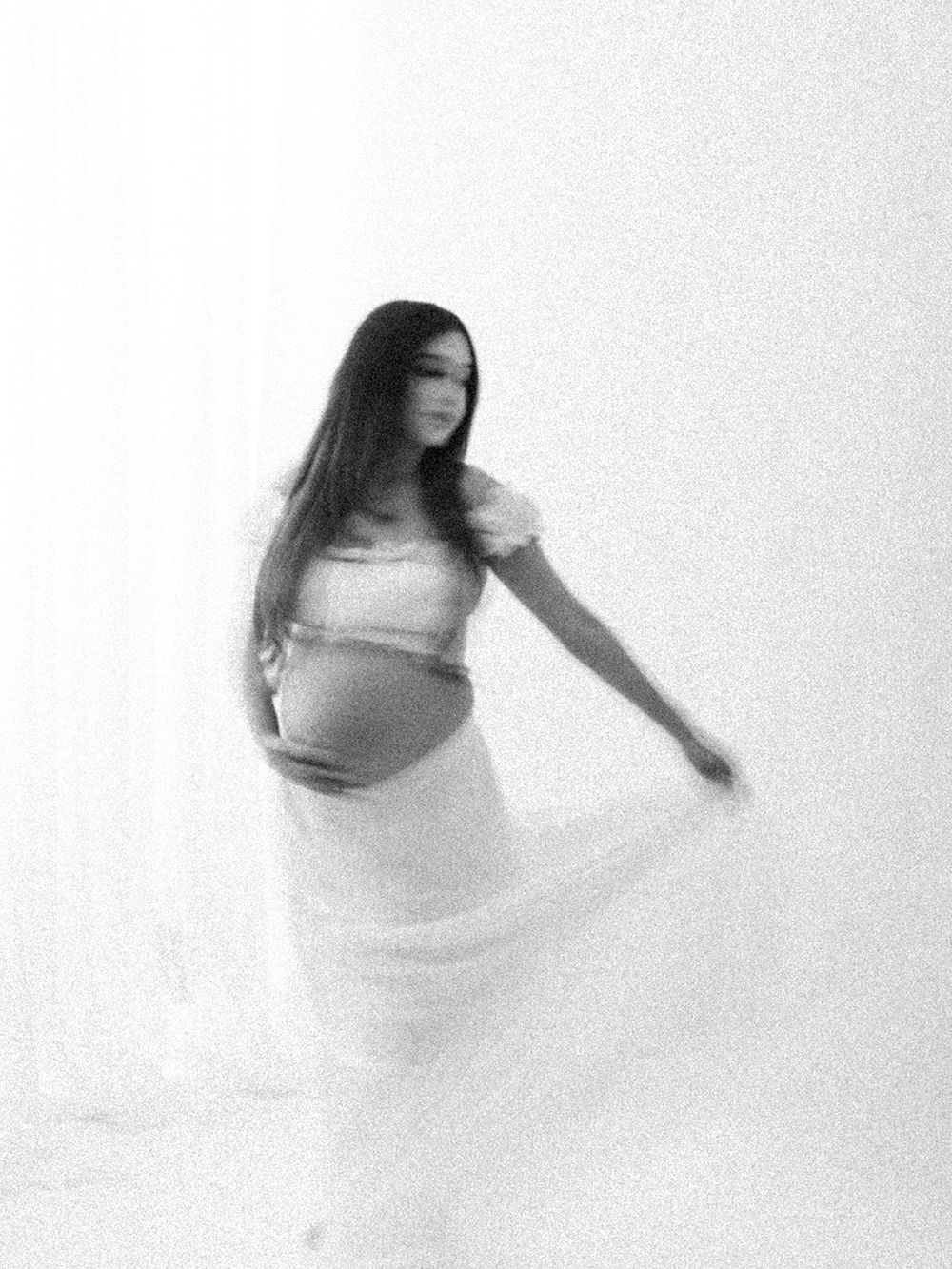 Artistic black and white sequence showing ethereal motion blur of a figure in white fabric creating flowing shapes.