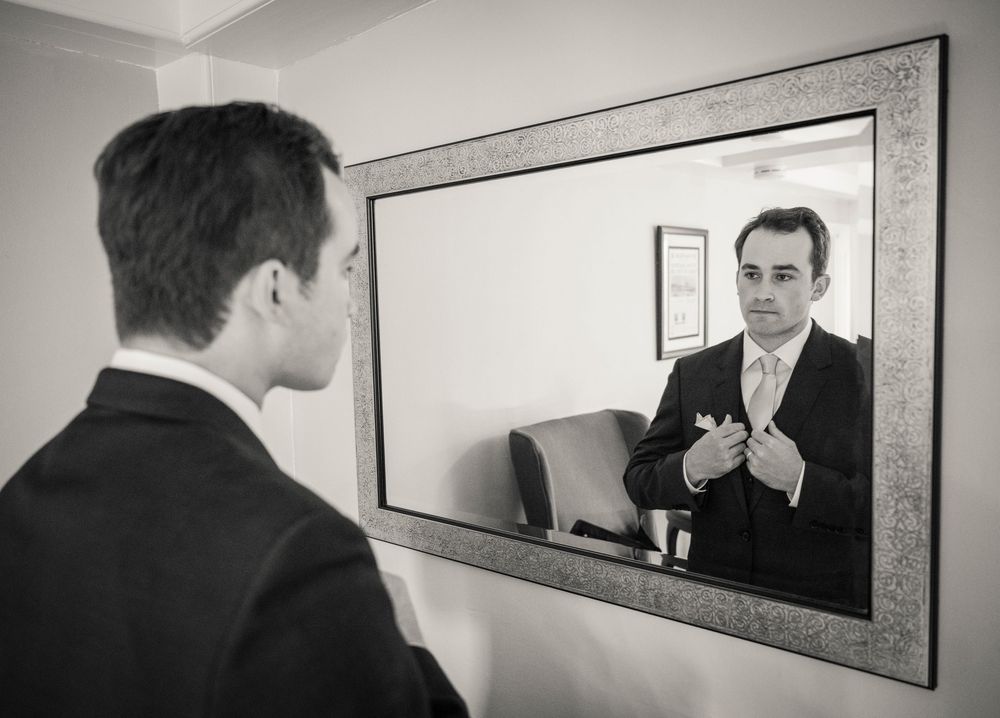 A black and white reflection of formal attire in an elegant framed mirror.