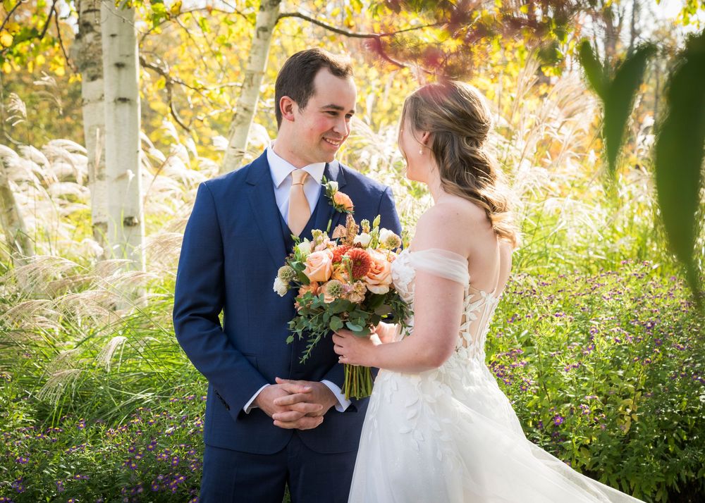 A couple shares a tender moment in an autumn setting with golden sunlight filtering through aspen trees.
