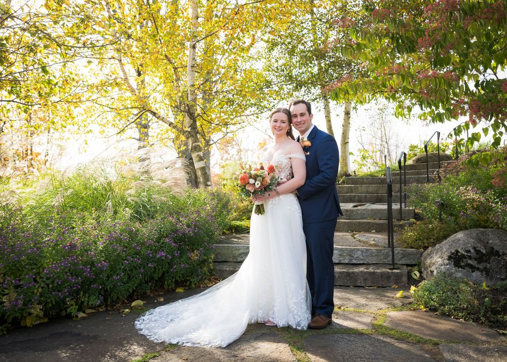 A romantic autumn wedding portrait with golden sunlight filtering through trees.