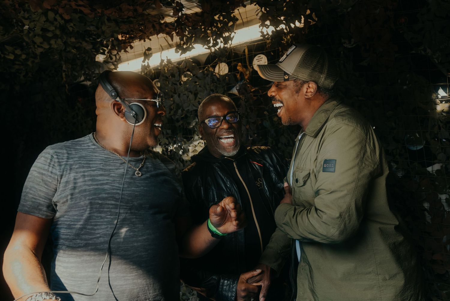 Three people sharing a laugh and conversation outdoors while wearing casual attire.